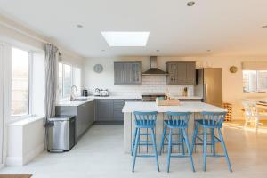 een keuken met blauwe krukken op een keukeneiland bij 4BR Beach House sleeps 10 - 5 mins walk to the Sea in West Wittering