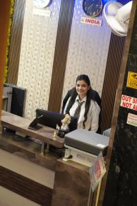 een man zit aan een bureau in een hokje bij Hotel Royal Inn igi in New Delhi