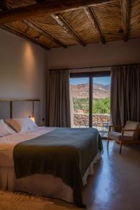a bedroom with a bed and a large window at Las Terrazas Hotel Boutique in Tilcara