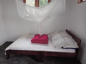 Bett mit rotem Kissen auf einem Zimmer in der Unterkunft Wakanda cottage kibale in Fort Portal
