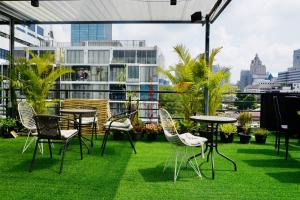 a patio with chairs and tables on the grass at Silom Soi 3 Hip and funky apartment with rooftop view in Bangkok