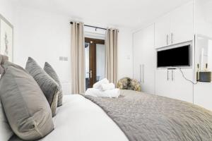 a white bedroom with a bed with a tv on the wall at Notting Hill 2BR Gem l Stylish Prime Apt in London