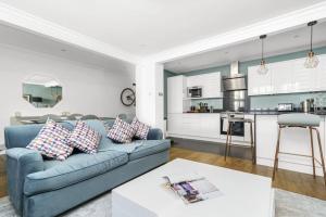 a living room with a blue couch and a kitchen at Notting Hill 2BR Gem l Stylish Prime Apt in London
