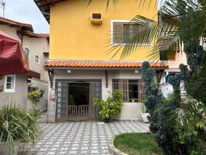 una casa amarilla con una entrada delante de ella en Quarto com / Bosque / Estoril / SJC, en São José dos Campos