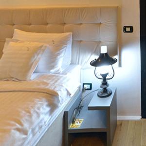 a bed with a table with a lamp on it at Ambra Boutique Hotel & Bistro in Constanţa