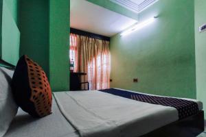 a bedroom with a bed with green walls and a window at SPOT ON Hotel Rock View Lodge in Tiruchchirāppalli