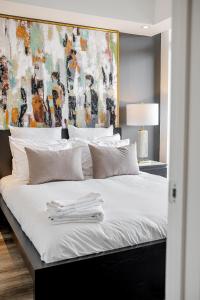 a bedroom with a large white bed with a painting on the wall at Westview Luxury Suites in Ottawa