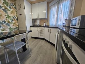 619A Moderno y acogedor apartamento في أوفِييذو: مطبخ فيه دواليب بيضاء وكرسي فيه