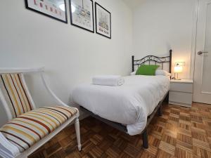 619A Moderno y acogedor apartamento في أوفِييذو: غرفة نوم بسرير ذو شراشف بيضاء ومخدات خضراء