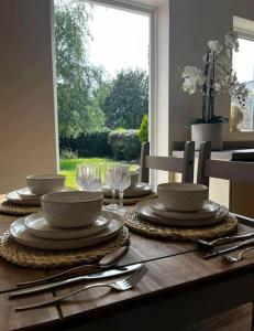 a wooden table with plates and utensils on it at Bonningtons - Charming 2 Bed Property In Brentwood in Shenfield