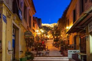 a city street at night with tables and chairs at Superb Acropolis View From A Central Brand New Apt in Athens