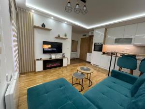 a living room with a blue couch and a kitchen at Apartman Plavi bor in Zlatibor