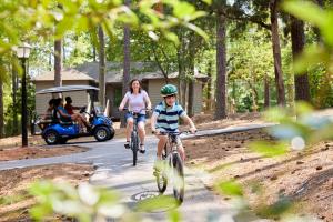 a woman and a child riding bikes with a golf cart at Callaway Resort & Gardens in Pine Mountain