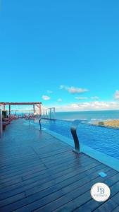 una piscina con el océano en el fondo en Paiva Home Stay - Bugan Paiva by Flatbpaiva, en Recife