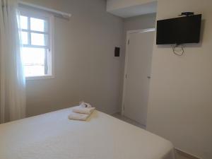 a white bedroom with a bed with two towels on it at Pousada Villa Encanto in Juquei