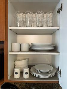 a cupboard filled with plates and bowls and glasses at Marco Polo Beach Resort Condo with balcony in Sunny Isles Beach