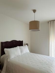 a bedroom with a white bed with a white comforter at Hospedería Nieves Centro in Chipiona
