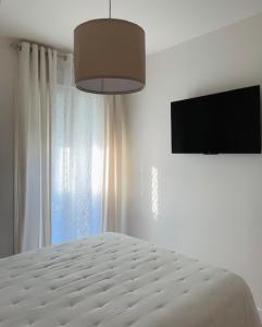 a bedroom with a bed and a flat screen tv at Hospedería Nieves Centro in Chipiona