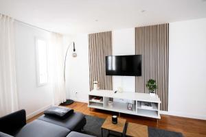 Una sala de estar con un sofá y un televisor en una pared. en Av REPUBLIQUE Design and cozy, en Aubervilliers