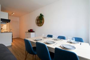 einen Esstisch mit blauen Stühlen und einem weißen Tisch in der Unterkunft 3-bedroom 3 bathrooms renovated in 2023 in Tourcoing
