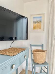 a tv sitting on top of a dresser with a chair at Driftwood in Gurnard