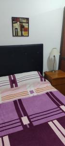 - un lit avec une couverture violette et blanche dans l'établissement Departamento Plaza Colón, súper equipado a una cuadra del mar, à Mar del Plata