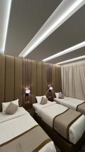 a room with three beds and lights on the ceiling at النخيل رست in Al Shafa