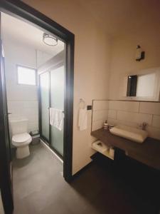 a bathroom with a toilet and a sink and a mirror at Apartamento #10 Portal de Occidente in Quetzaltenango