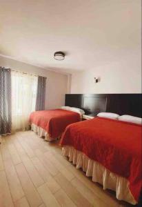 2 Betten in einem Hotelzimmer mit roten Decken in der Unterkunft Apartamento #10 Portal de Occidente in Quetzaltenango