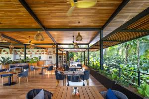 ein Restaurant mit Tischen, Stühlen und Pflanzen in der Unterkunft El Remanso Rainforest Lodge in Puerto Jiménez