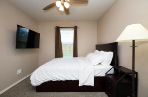 um quarto com uma cama, uma ventoinha de tecto e uma janela em Downtown Elegance: 2-BR Home - San Angelo, Texas em San Angelo