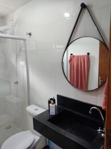 a bathroom with a sink and a mirror over a toilet at Pereira Sell Pousada in Garopaba