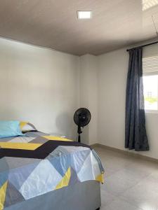 a bedroom with a bed and a fan next to a window at Edificio Pacifica Aptos in Cali