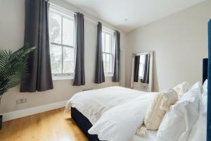 a bedroom with a white bed and windows at Stylish & Modern London Apartment in Honor Oak in London