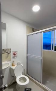 a bathroom with a toilet and a glass shower stall at Edificio Pacifica Aptos in Cali