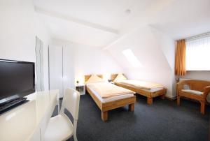 a room with two beds and a flat screen tv at Hotel Garni Schilling in Duisburg