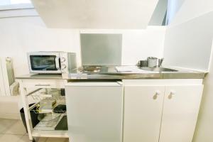 a white kitchen with a sink and a microwave at The Champo studio Near the city centre #B2 in Grenoble