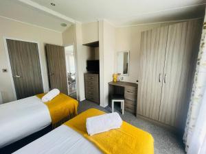 a hotel room with two beds with yellow blankets at Waterside Retreat With Hot Tub in Pocklington