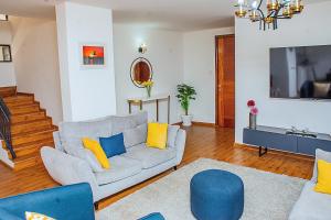 a living room with a couch and blue and yellow pillows at Casa Misa Riverside Duplex in Nairobi