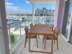 una mesa de madera y sillas en un balcón con puerto deportivo en Deluxe Marina View Seafront Gibraltar Stay, en Gibraltar