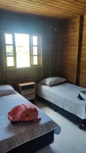 a bedroom with two beds and a bag on the floor at Pereira Sell Pousada in Garopaba
