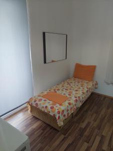 Cama pequeña en habitación con suelo de madera en Kjara Apartments, en Tivat