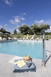 a hat and sunglasses sitting next to a swimming pool at Camping Les Nysades in Mirepoix