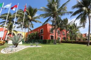 un edificio rojo con palmeras delante en Bahia Principe Luxury Sian Ka´an - Adults Only - All Inclusive, en Akumal