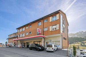 un edificio con dos coches estacionados frente a él en Gemütliche Ferienwohnung direkt an der Skipiste, en Wildhaus