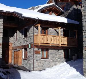 a log cabin with a wooden deck in the snow at Chalet Le Choucas N°1 in Levassaix