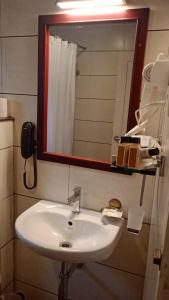 a bathroom sink with a mirror and a phone at HOTEL PALAZHI in Pattanapuram