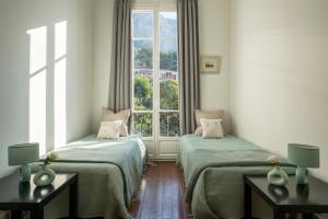 two beds in a room with a window at Villa Fantaisie in Menton