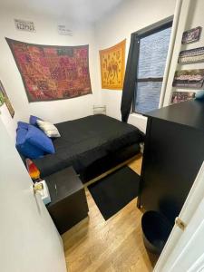 Charming One-Bedroom Apartment in South Chelsea في نيويورك: غرفة نوم صغيرة مع سرير أسود ونافذة