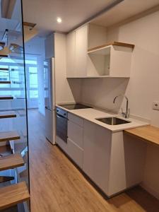 a kitchen with white cabinets and a sink and a table at Casa de Ángeles in Fisterra